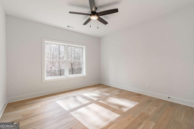 empty room featuring baseboards, a ceiling fan, light wood finished floors, and visible vents
