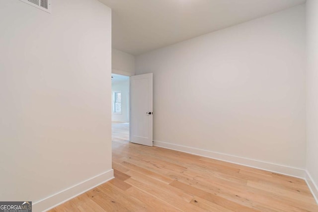 empty room featuring baseboards, light wood-style floors, and visible vents