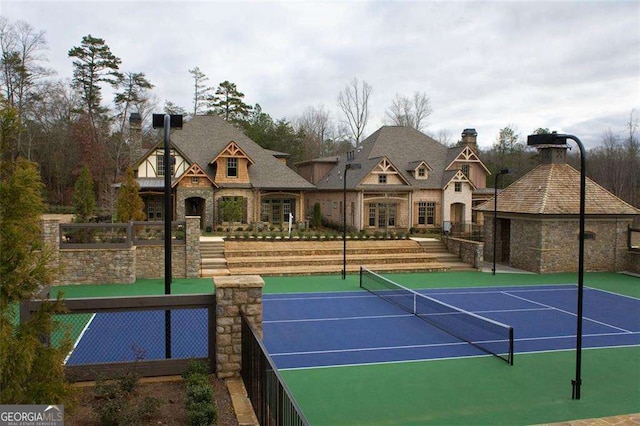view of tennis court with community basketball court and fence