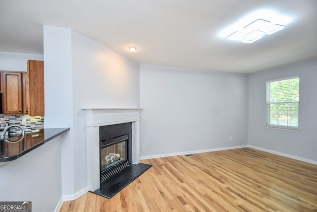 2201 Landing Walk Dr, Duluth, GA 30097 - unfurnished living room featuring baseboards, light wood-style flooring, a glass covered fireplace, and visible vents