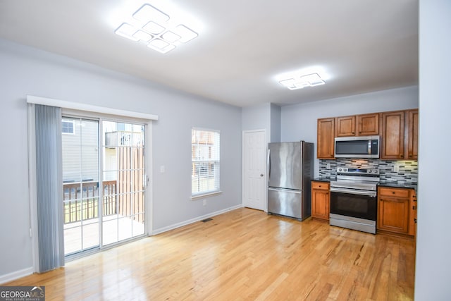 2201 Landing Walk Dr, Duluth, GA 30097 - kitchen with decorative backsplash, brown cabinetry, dark countertops, appliances with stainless steel finishes, and light wood finished floors