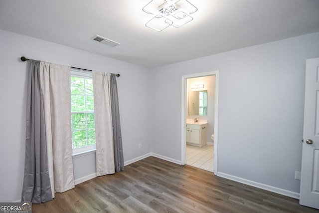 2201 Landing Walk Dr, Duluth, GA 30097 - unfurnished bedroom featuring a sink, ensuite bath, baseboards, wood finished floors, and visible vents