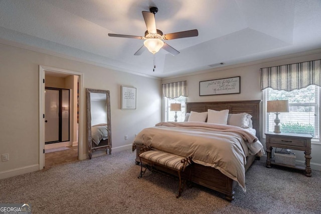 carpeted bedroom with visible vents, crown molding, baseboards, a tray ceiling, and a ceiling fan