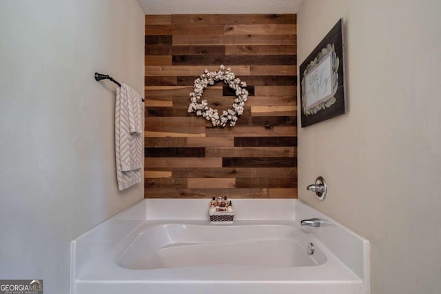 bathroom featuring wood walls and a bath