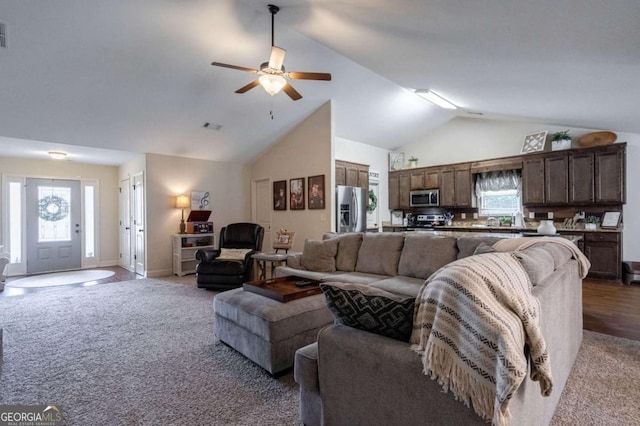 carpeted living room with a ceiling fan, high vaulted ceiling, plenty of natural light, and baseboards