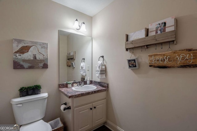 half bath featuring vanity, baseboards, and toilet