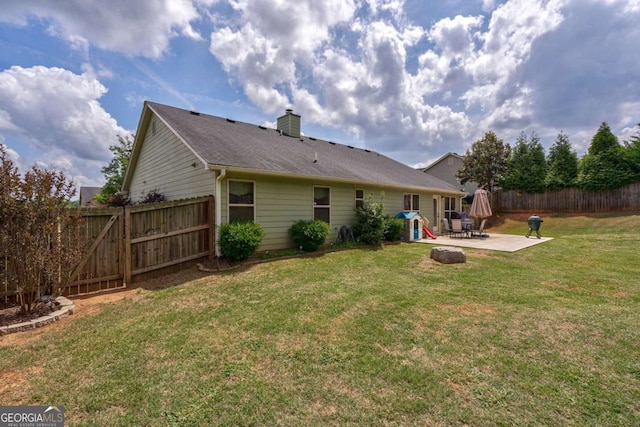 rear view of property with fence, a chimney, a yard, and a patio area