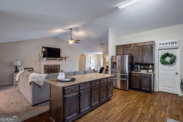 kitchen with ceiling fan, stainless steel refrigerator with ice dispenser, vaulted ceiling, dark brown cabinets, and open floor plan