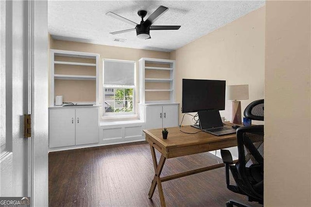 home office featuring dark wood-style flooring, a textured ceiling, visible vents, and a ceiling fan