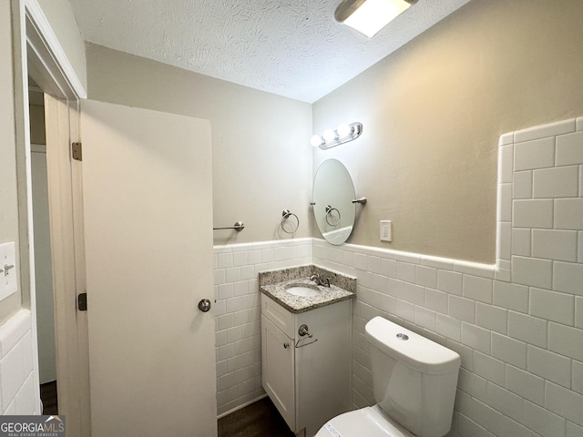6507 Jackie Ln, Austell, GA 30106 - half bathroom featuring vanity, wainscoting, toilet, tile walls, and a textured ceiling