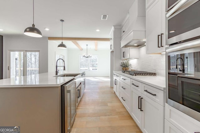 kitchen featuring light wood finished floors, beverage cooler, recessed lighting, stainless steel appliances, and custom exhaust hood
