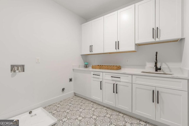 laundry room featuring baseboards, a sink, cabinet space, and hookup for an electric dryer