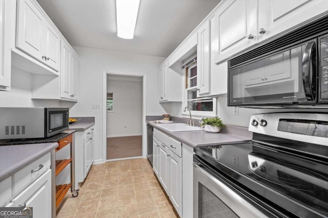 kitchen featuring white cabinets, stainless steel appliances, baseboards, and a sink