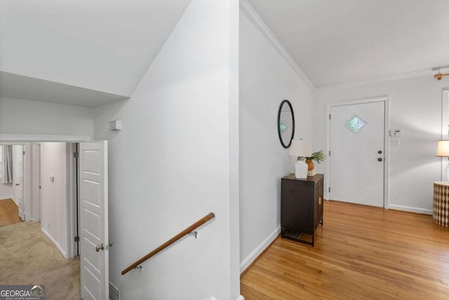 entrance foyer with crown molding, baseboards, and light wood-style floors