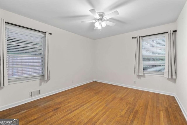 unfurnished room with visible vents, a ceiling fan, baseboards, and wood finished floors