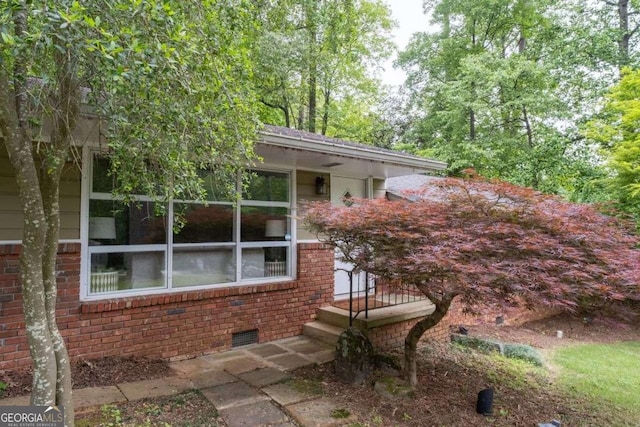 view of home's exterior with brick siding and crawl space