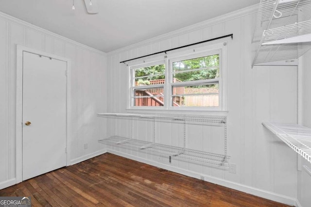 unfurnished room with ornamental molding, a decorative wall, and dark wood finished floors