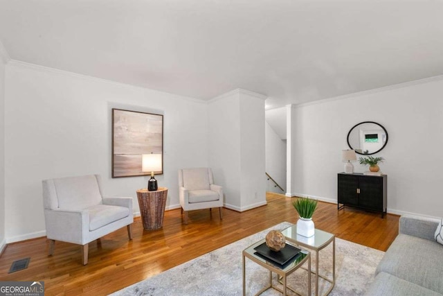 living area with crown molding, baseboards, visible vents, and wood finished floors