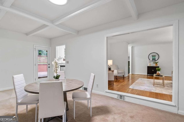 carpeted dining space with baseboards, wood finished floors, beam ceiling, and visible vents