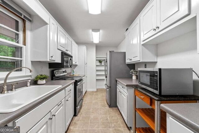 kitchen with stainless steel appliances, baseboards, white cabinetry, and a sink