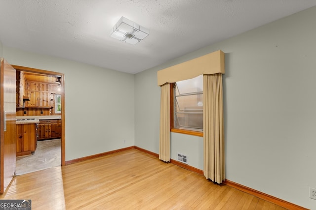unfurnished room featuring visible vents, light wood finished floors, and baseboards