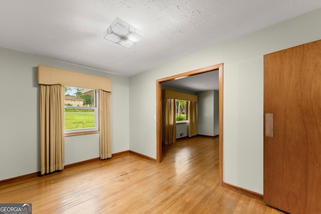 spare room featuring a healthy amount of sunlight, baseboards, and light wood-style flooring