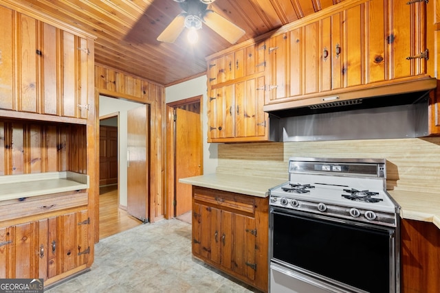 kitchen with light floors, gas range, light countertops, under cabinet range hood, and brown cabinets