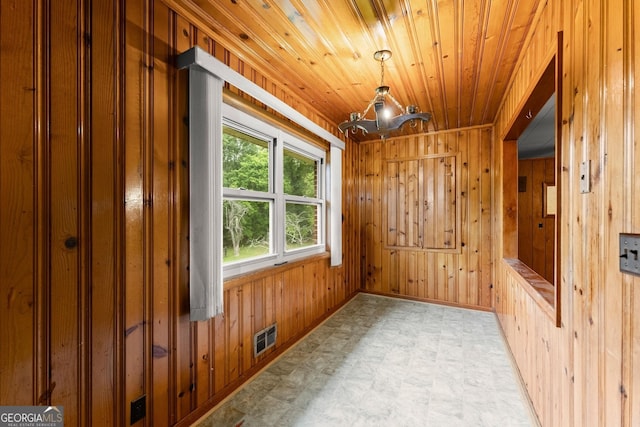 unfurnished room with wood ceiling, visible vents, a chandelier, wooden walls, and light floors