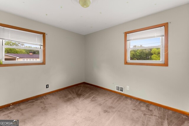 carpeted spare room featuring baseboards and visible vents