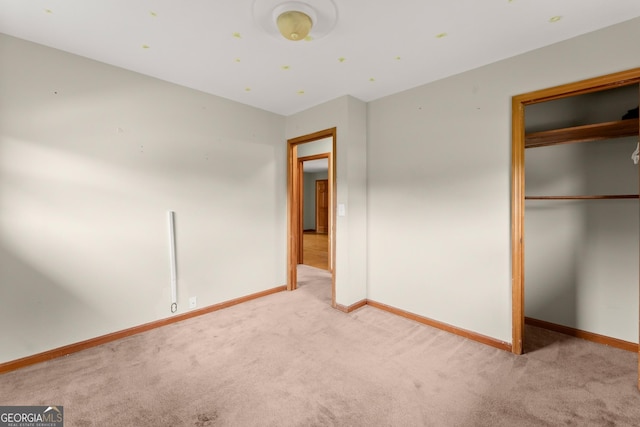 unfurnished bedroom with baseboards, carpet, and a closet