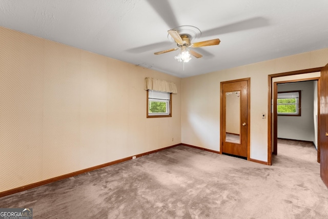 empty room featuring carpet floors, plenty of natural light, and baseboards