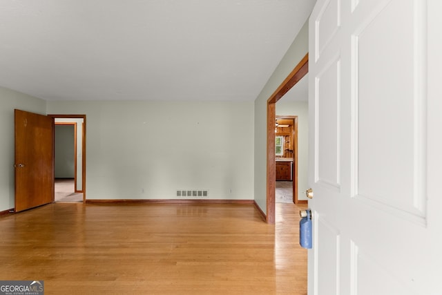 spare room with baseboards, visible vents, and light wood finished floors