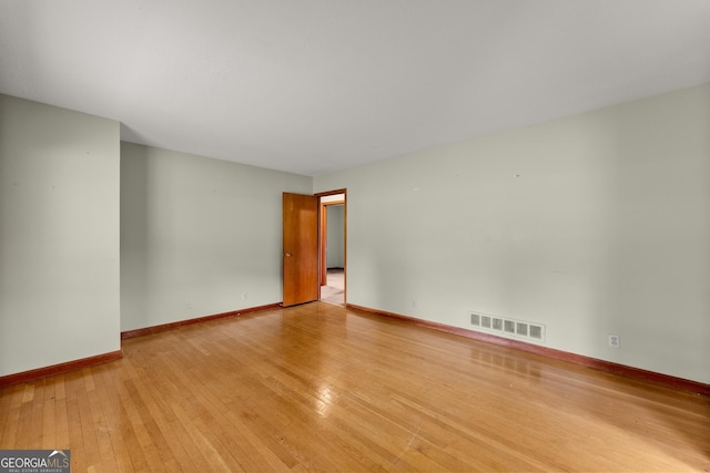 unfurnished room featuring wood-type flooring, baseboards, and visible vents