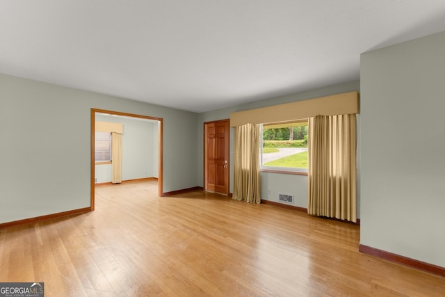 empty room with visible vents, light wood-style floors, and baseboards