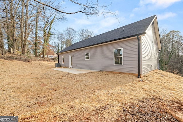 back of property with roof with shingles and a patio area