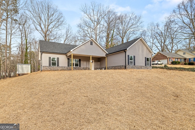 view of front of home featuring a shingled roof and stone siding