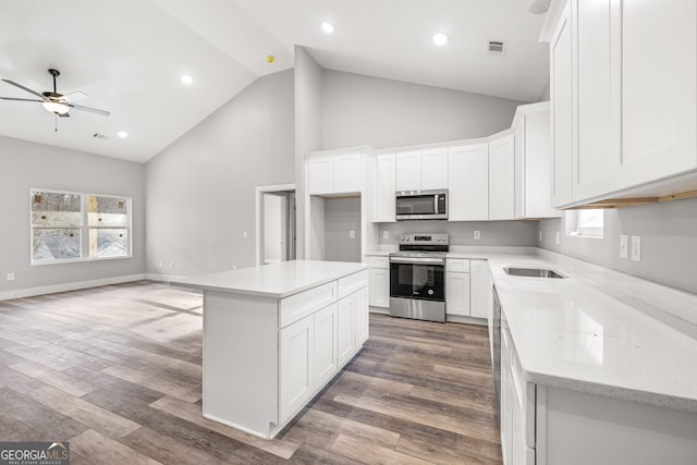 kitchen featuring high vaulted ceiling, stainless steel appliances, a ceiling fan, open floor plan, and wood finished floors