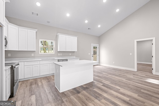 kitchen featuring electric range, light countertops, high vaulted ceiling, a center island, and visible vents