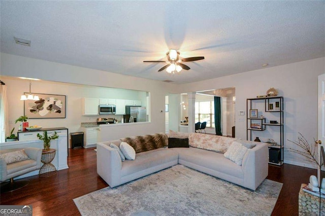 living area with dark wood-type flooring, baseboards, ceiling fan, and visible vents