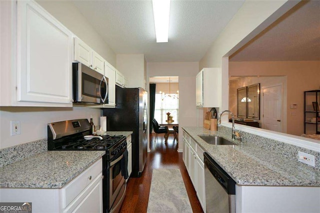 kitchen with light stone countertops, white cabinets, a sink, dark wood finished floors, and appliances with stainless steel finishes