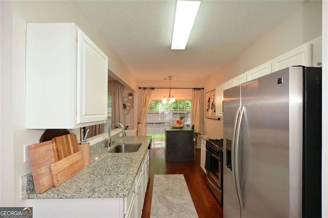 kitchen with light stone countertops, a sink, stainless steel appliances, white cabinetry, and dark wood-style floors