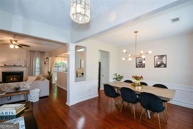 dining space with visible vents, wainscoting, a decorative wall, wood finished floors, and a warm lit fireplace