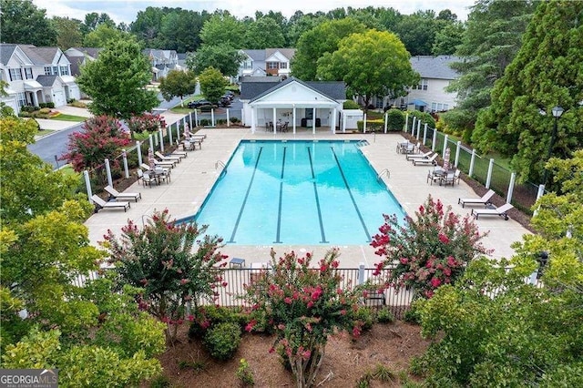 pool with a patio area, fence, and a residential view