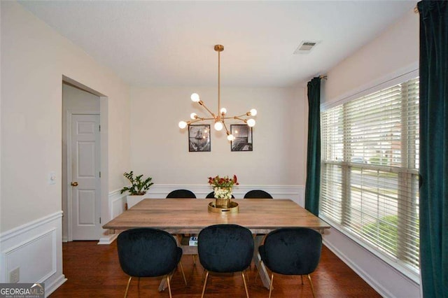 dining room with an inviting chandelier, wainscoting, wood finished floors, and visible vents