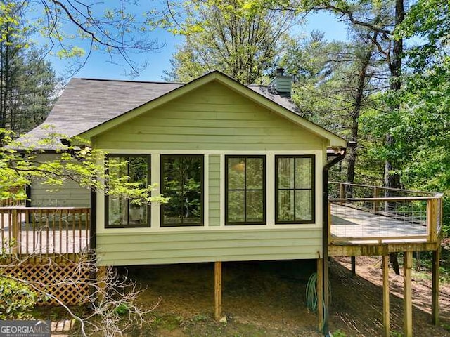 rear view of property with a chimney and a deck