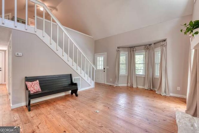 unfurnished living room with wood-type flooring, baseboards, and stairway