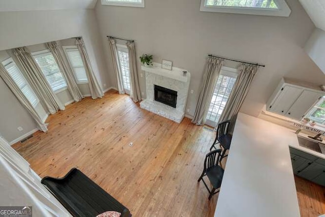 living room with high vaulted ceiling, a healthy amount of sunlight, and light wood-style flooring
