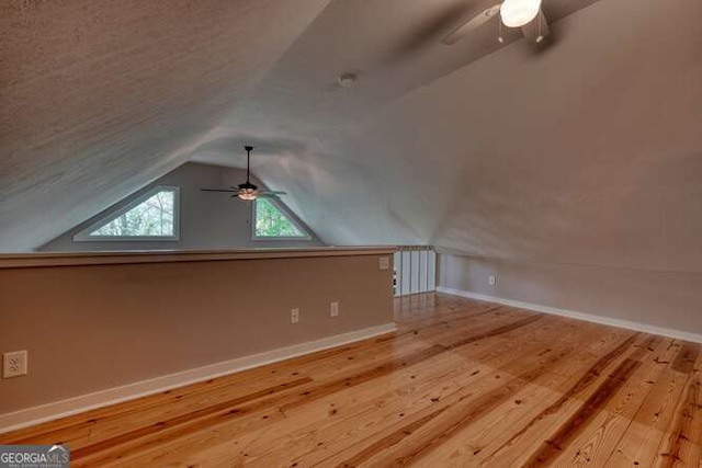 bonus room featuring wood finished floors, a ceiling fan, baseboards, and lofted ceiling