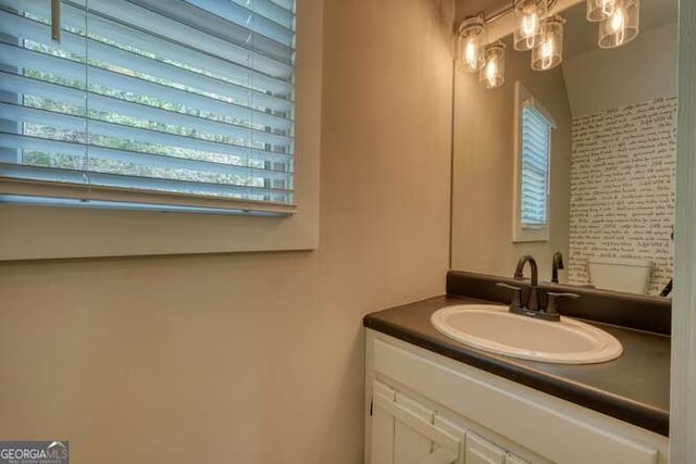 half bath featuring a healthy amount of sunlight, vanity, and toilet