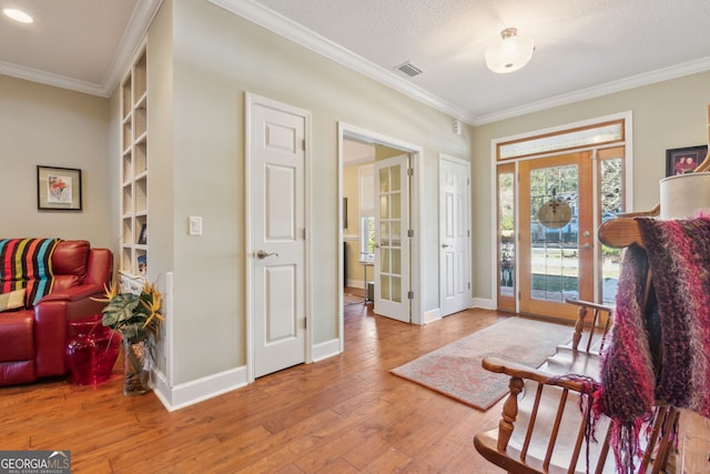 entrance foyer featuring wood-type flooring, visible vents, and ornamental molding